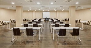 Ett konferensrum med flera bord och stolar, en whiteboard och en projektorduk.