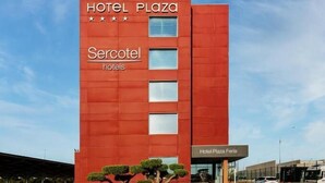 Un edificio de hotel rojo con el nombre 'Hotel Plaza' y la señalización 'Sercotel hotels'.