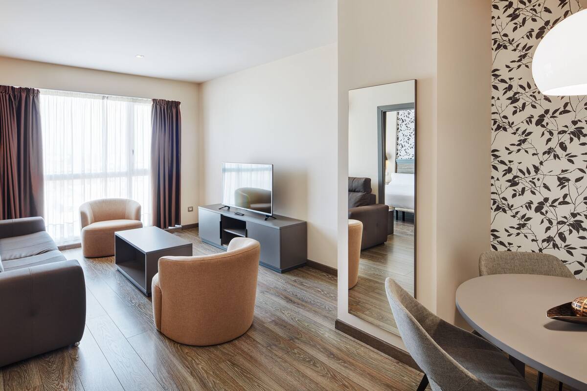 Un salon moderne avec un canapé, des fauteuils, une table basse et un téléviseur posé sur un meuble.