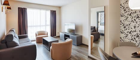 Una sala de estar moderna con un sofá, sillones, una mesa de centro y un televisor sobre un mueble.