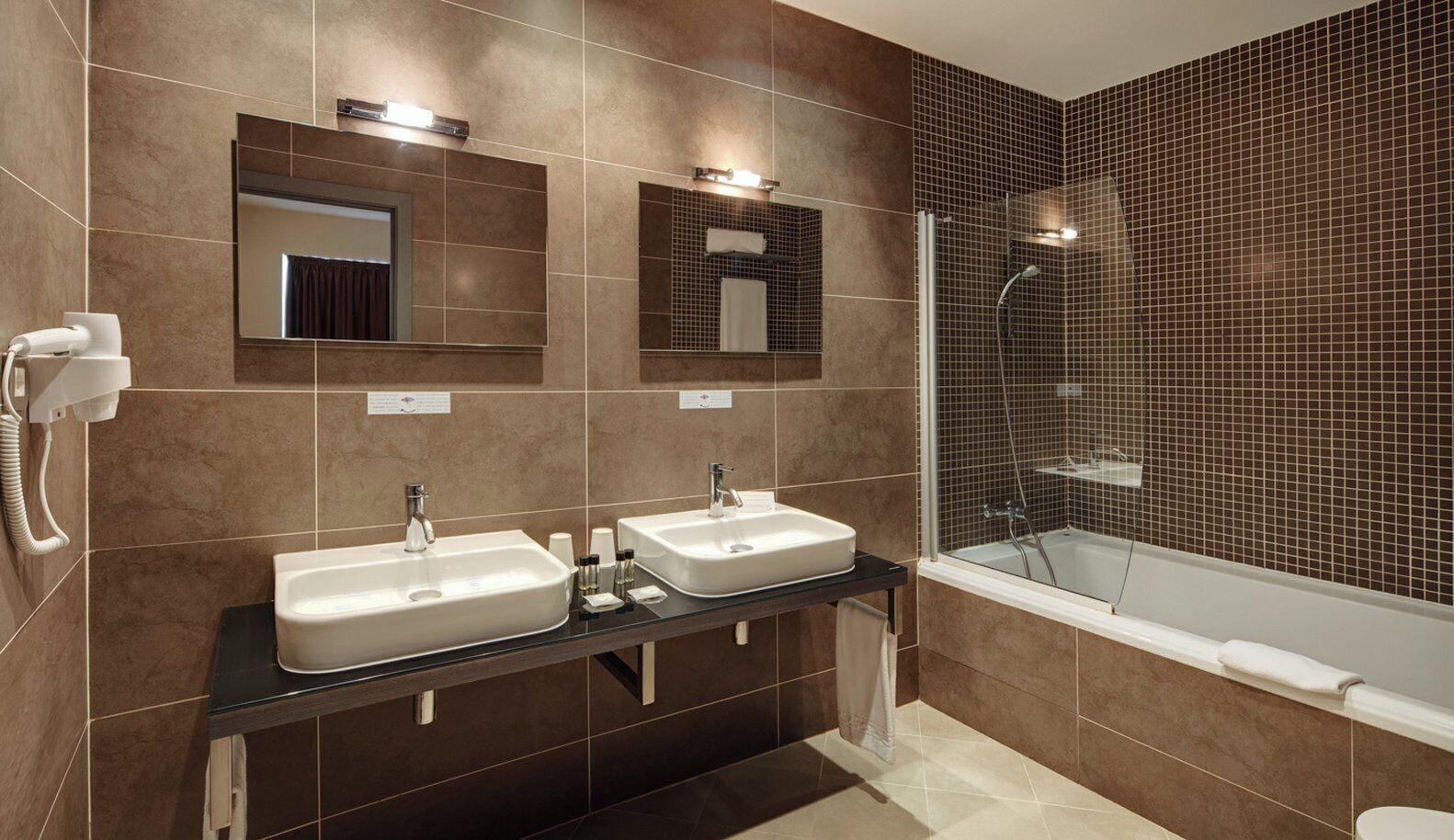 Ein modernes Badezimmer mit zwei Waschbecken, einem Spiegel und einer Duschkabine.