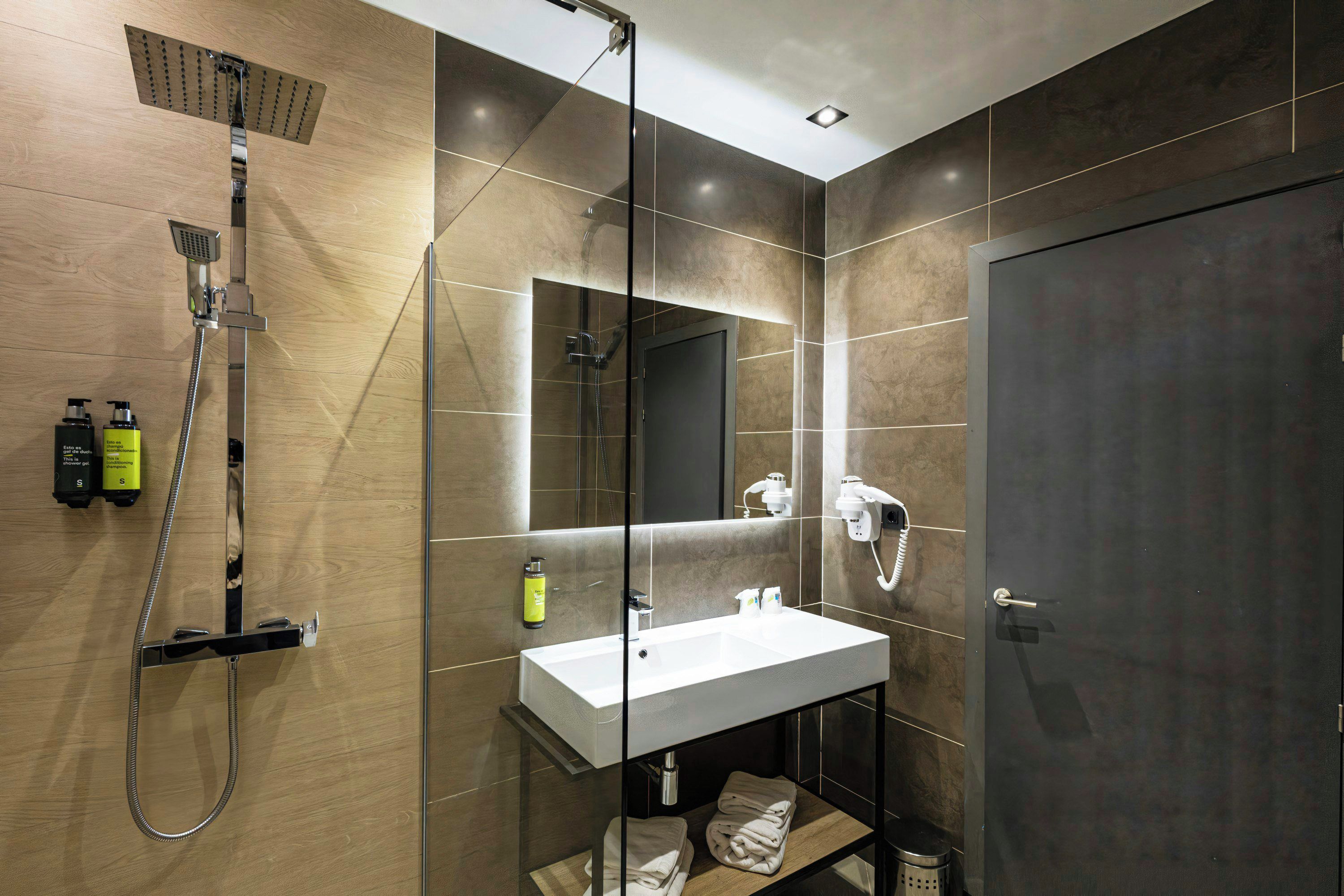 Un baño moderno con ducha, lavamanos y espejo.