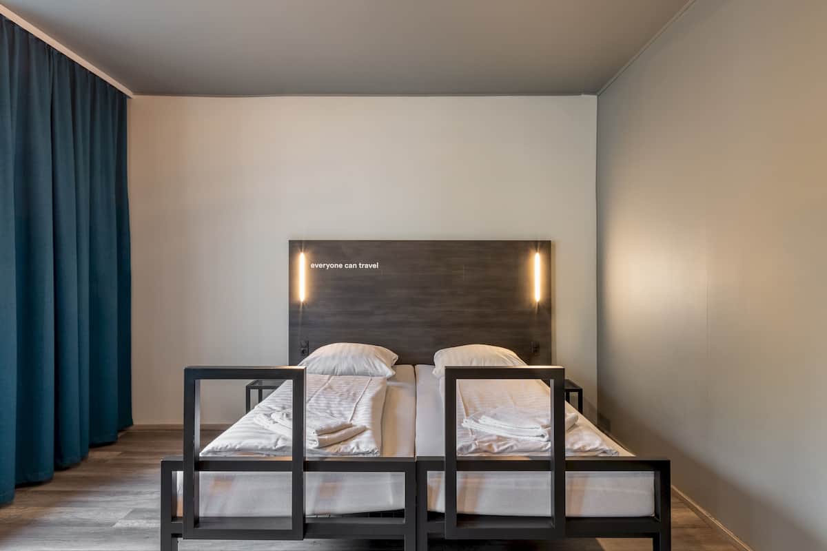 Una habitación de hotel con dos camas, un cabecero oscuro y un letrero en la pared.