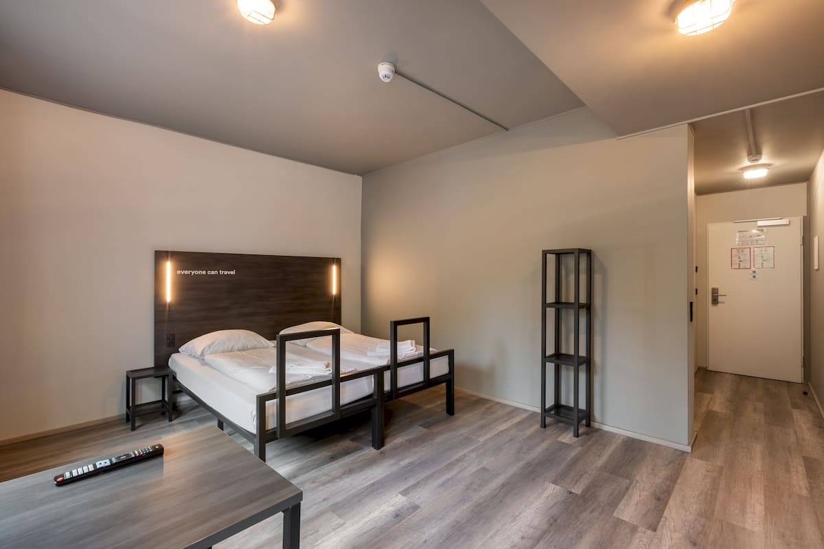Un dormitorio moderno con cama, mesitas de noche, escritorio y estantería.