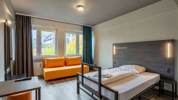 Una habitación de hotel moderna con cama, sofá, escritorio y vistas al exterior.
