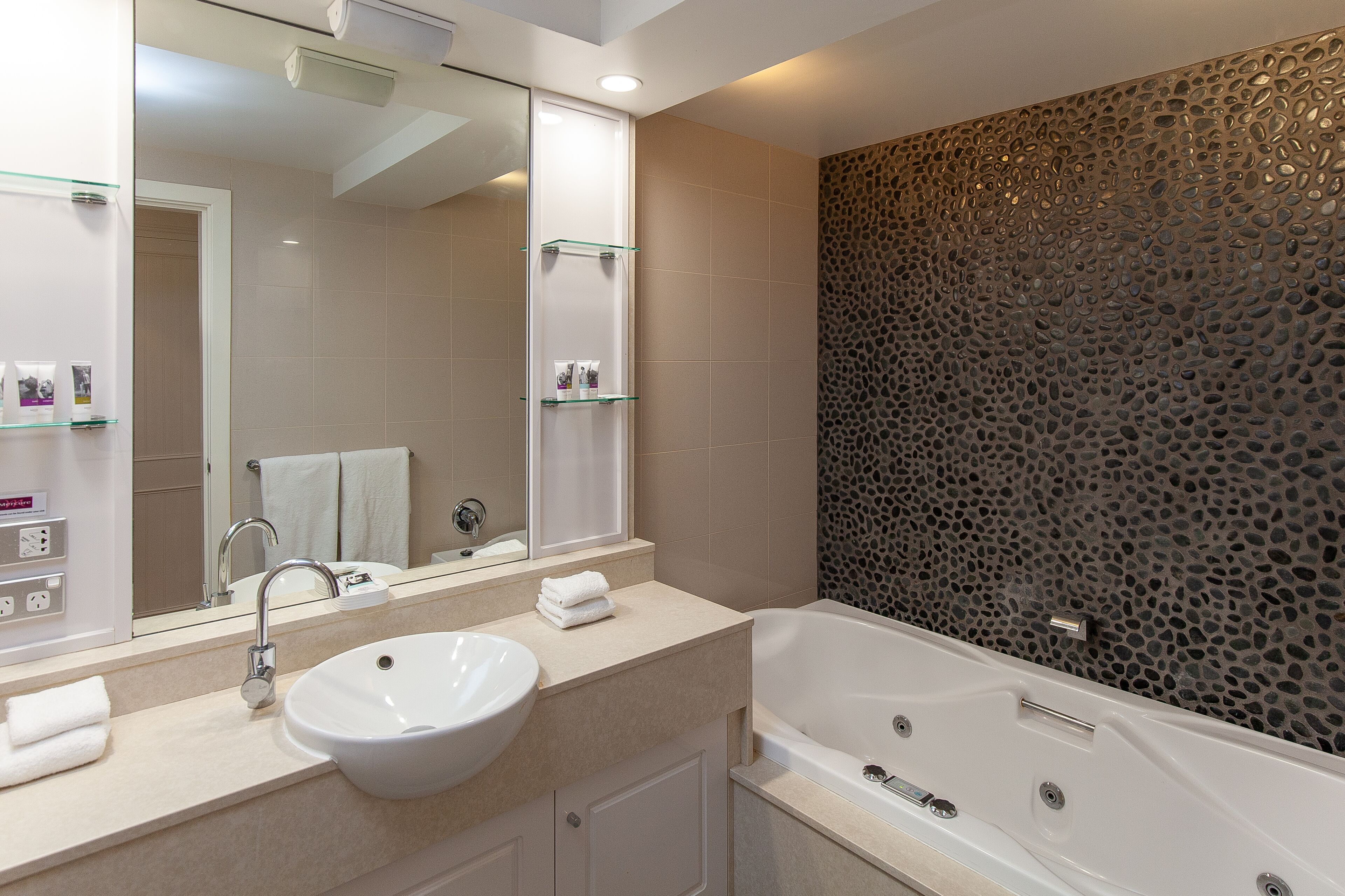 A modern bathroom with a large sink, mirror, and bathtub.