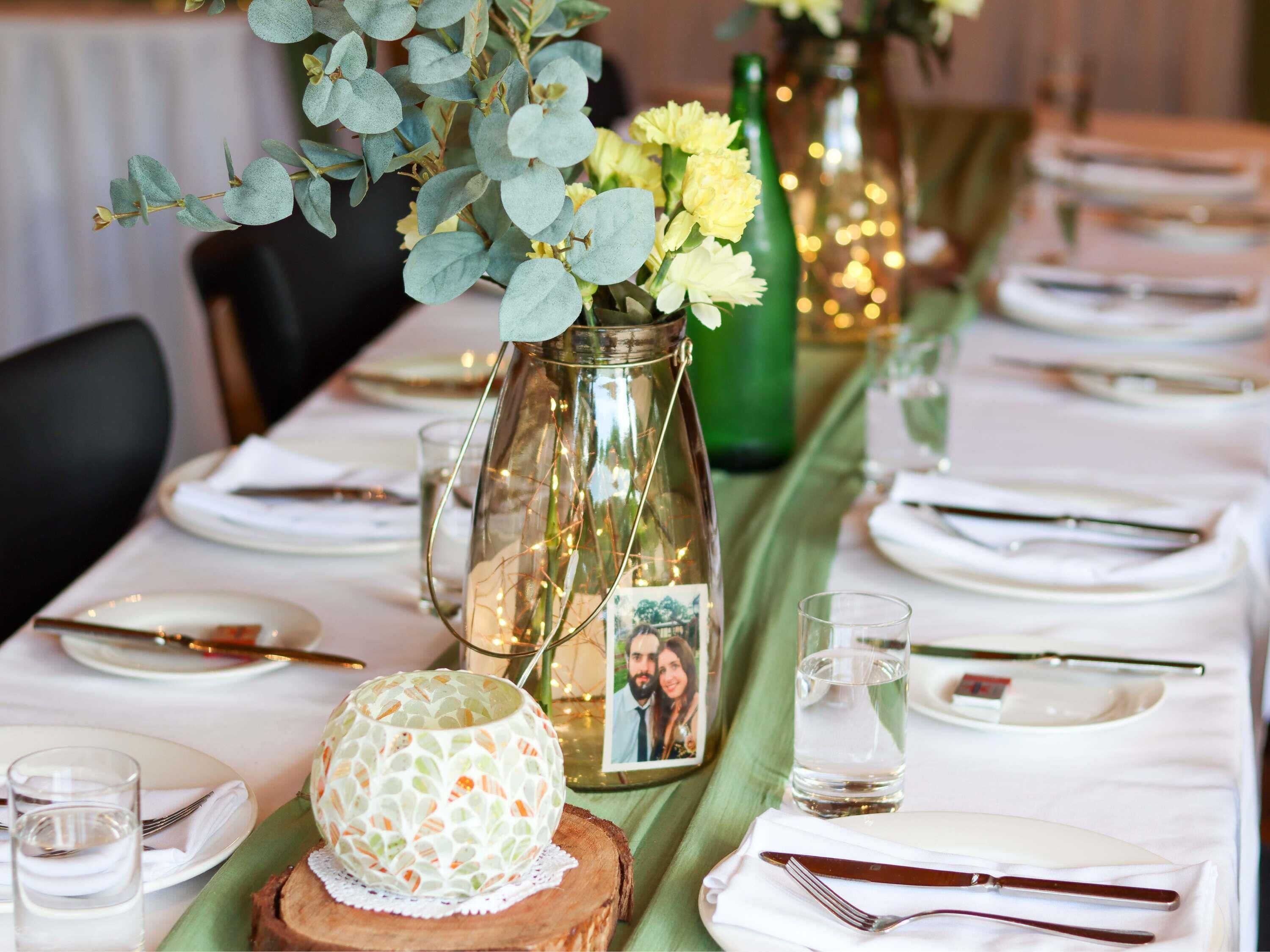 A table set for dining with a vase of flowers, a candle, and a decorative plate.