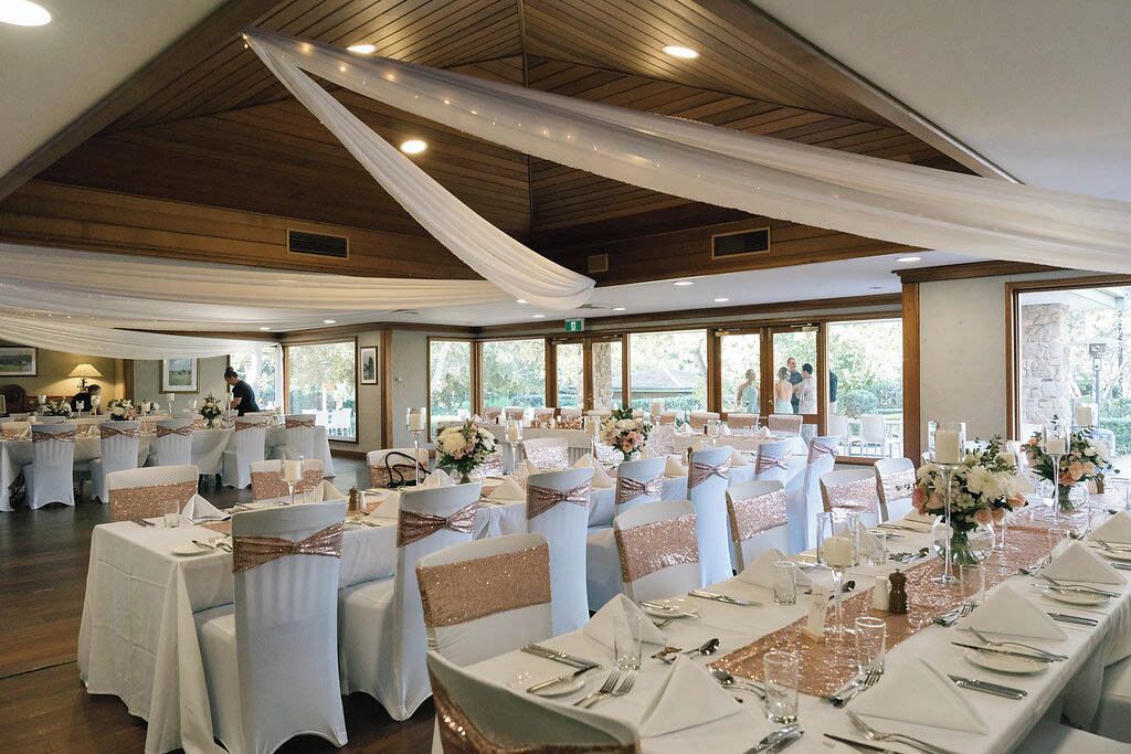 A banquet hall with tables set for a formal event, featuring white tablecloths, silverware, and floral centerpieces.