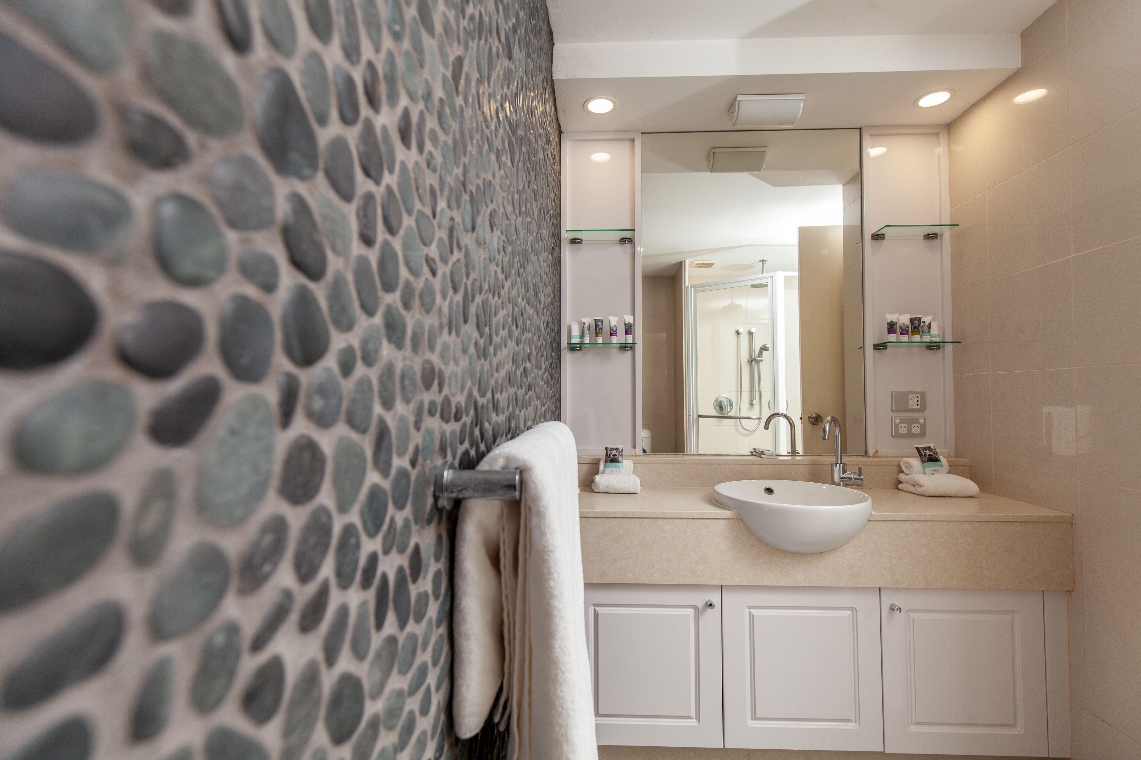 Un baño con pared de piedra, un lavabo y un espejo.