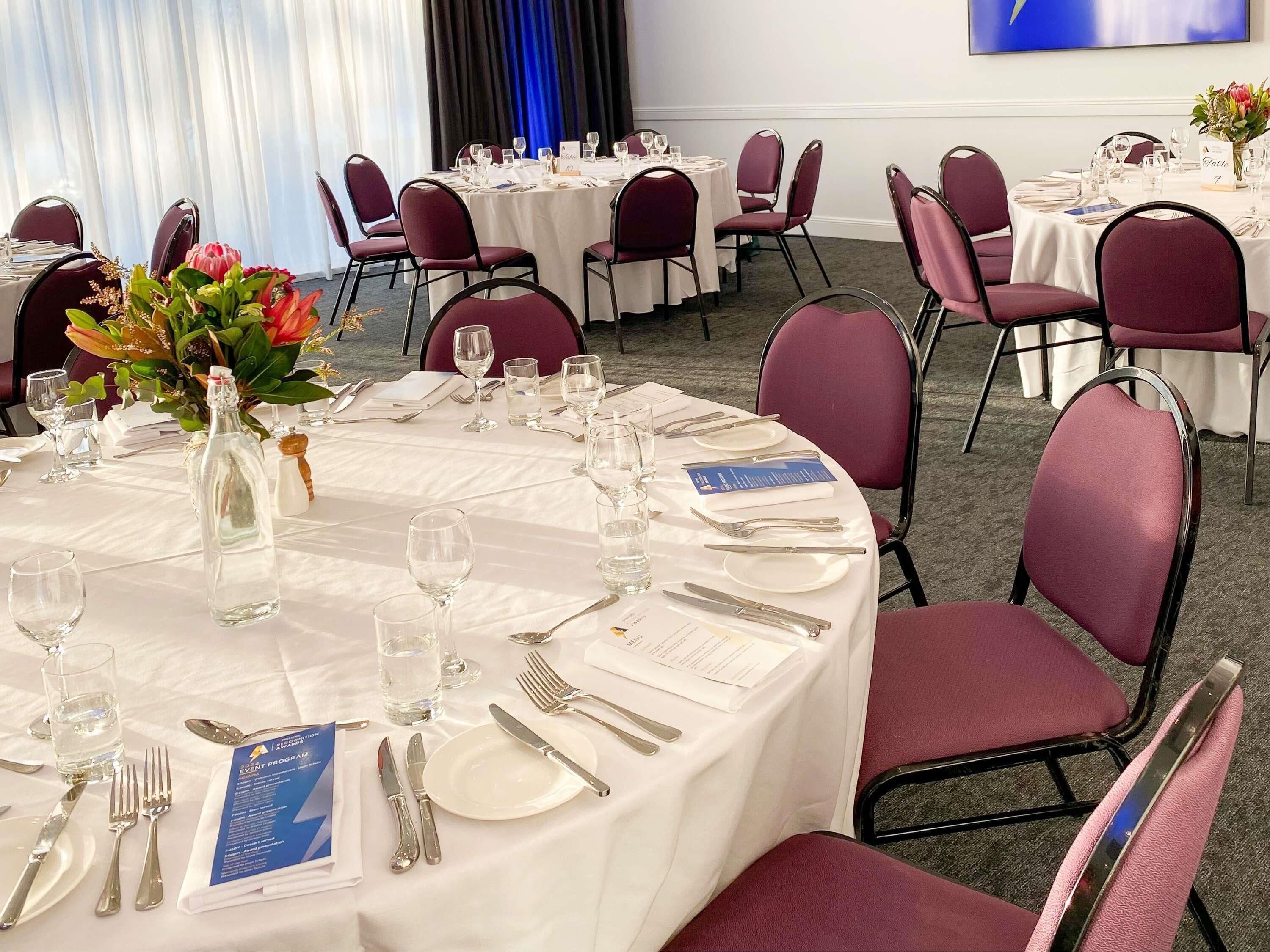 A conference room with round tables, chairs, and a large screen.