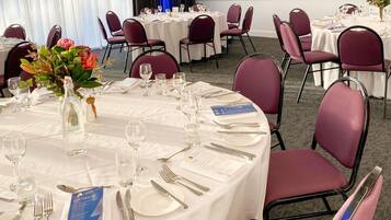 A conference room with round tables, chairs, and a large screen.