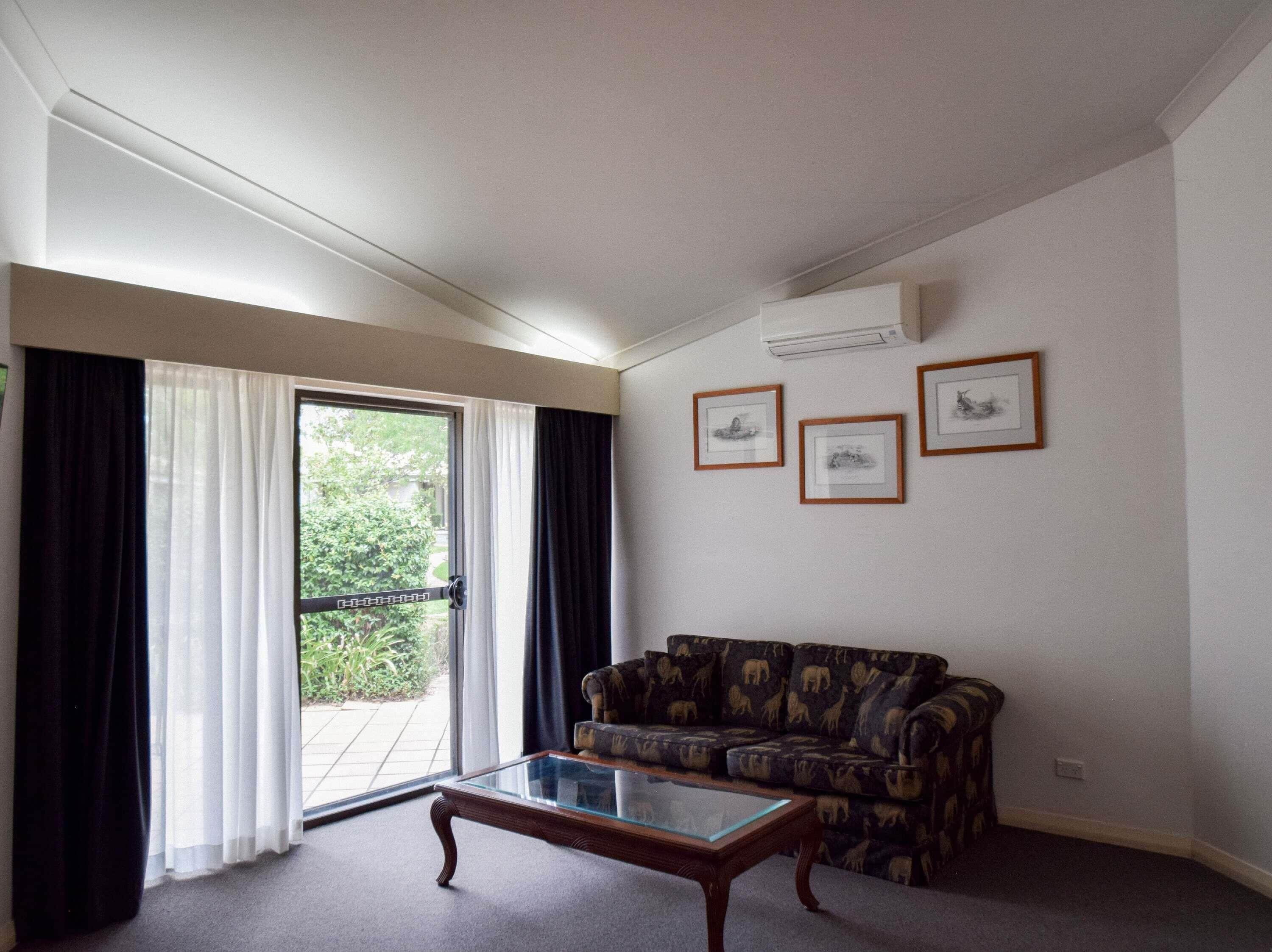 Una sala de estar con un sofá, una mesa de centro de vidrio y una puerta corrediza de vidrio que da a un balcón.