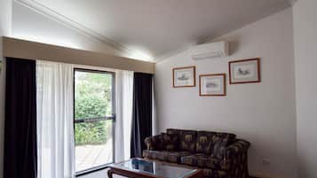 Una sala de estar con un sofá, una mesa de centro de vidrio y una puerta corrediza de vidrio que da a un balcón.
