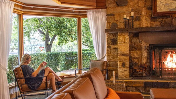 Una sala de estar acogedora con chimenea de piedra, sofás de cuero y un ventanal con vistas a un jardín.