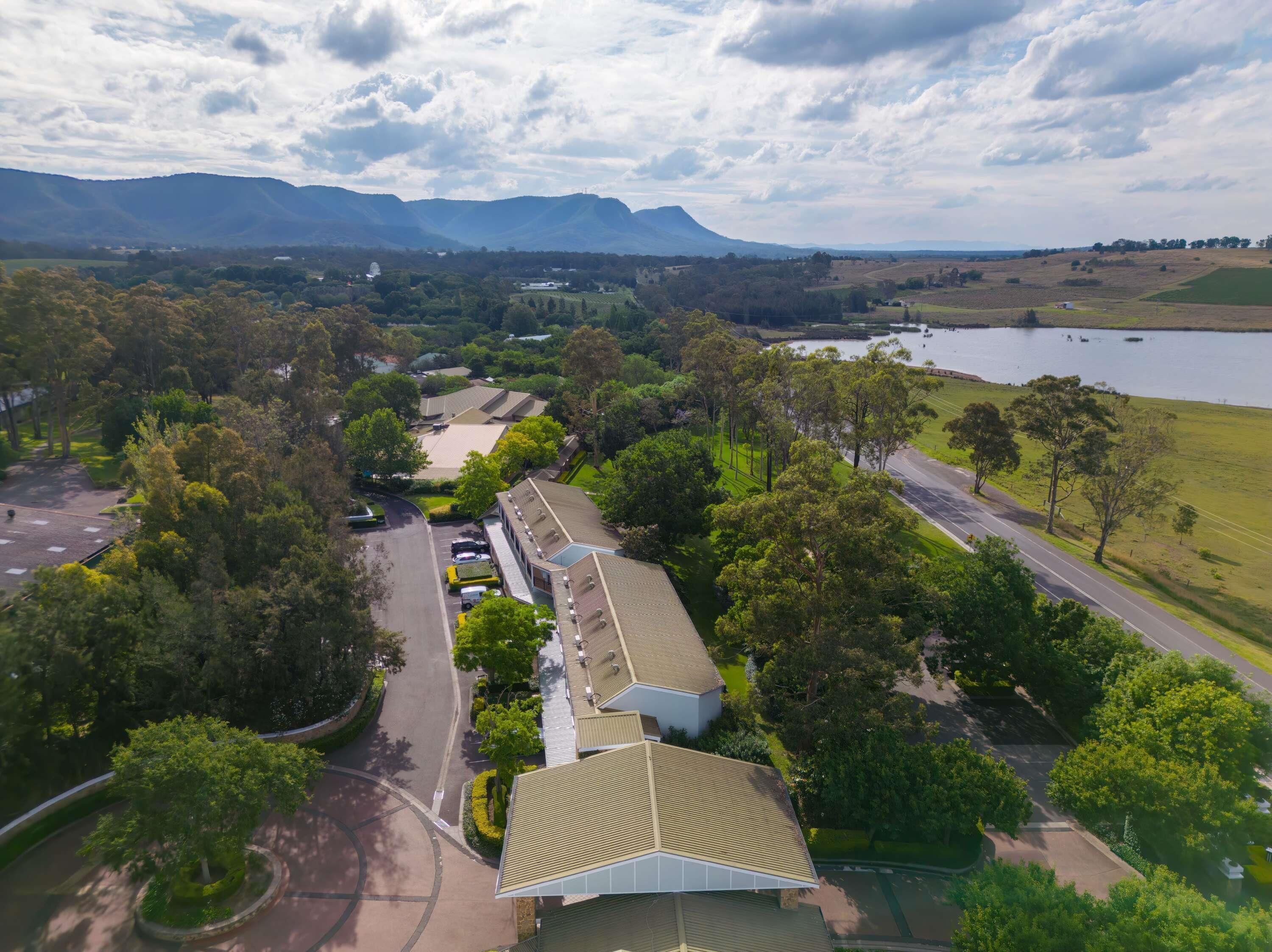 An aerial view of a property with a parking lot, a building with a green roof, and a lake in the background.