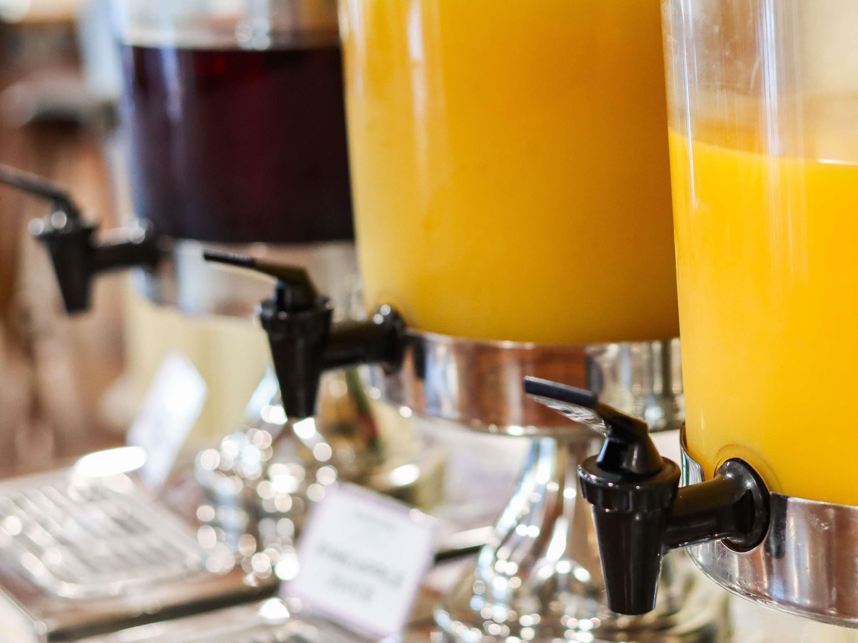 Um dispensador de suco com recipiente transparente e bico metálico.