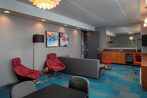 A modern lounge area with a sofa, two armchairs, a coffee table, and a small side table. - Aloft by Marriott Rogers-Bentonville (Rogers)