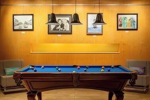 A pool table with balls, surrounded by two sofas, and framed artworks on the wall. - Aloft by Marriott Rogers-Bentonville (Rogers)