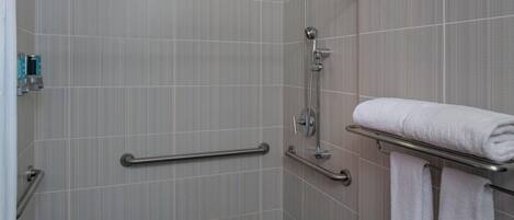 A bathroom with a shower, grab bars, a towel rack, and a toilet.