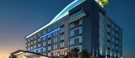 Un hotel de varios pisos con diseño moderno, que destaca por una entrada imponente con porche y una señalización visible.
