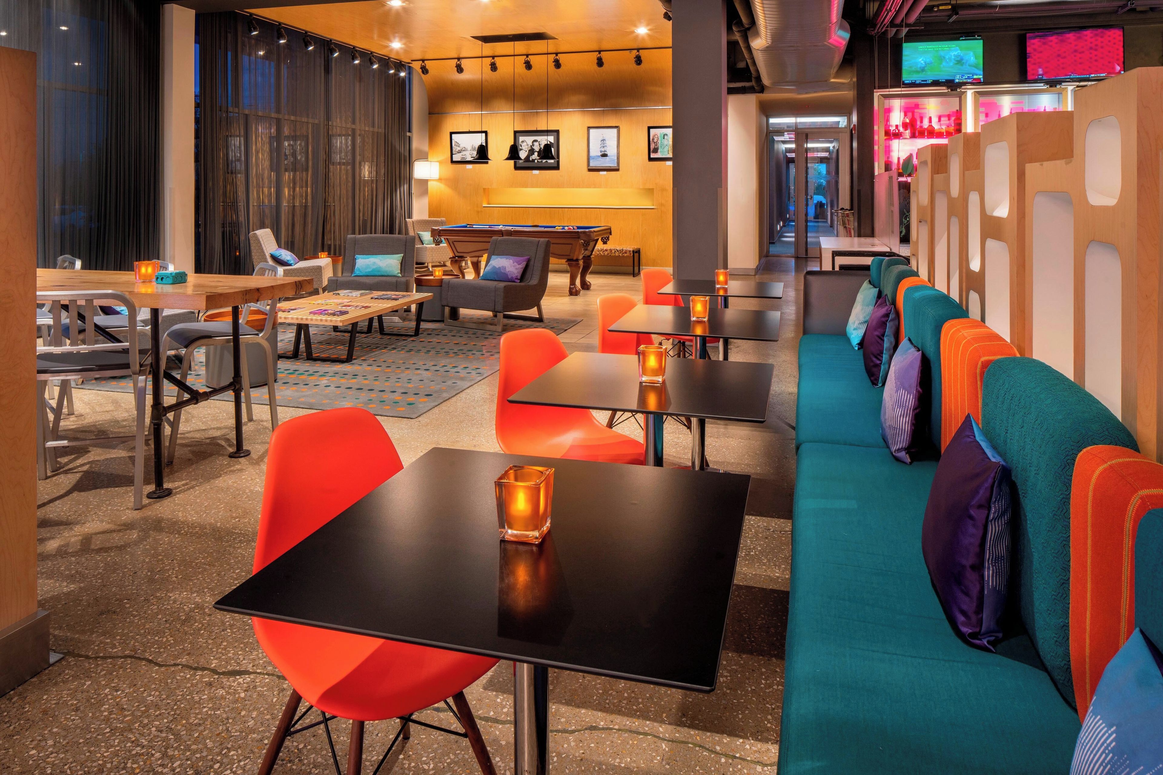A modern lounge area with seating, tables, and a pool table.
