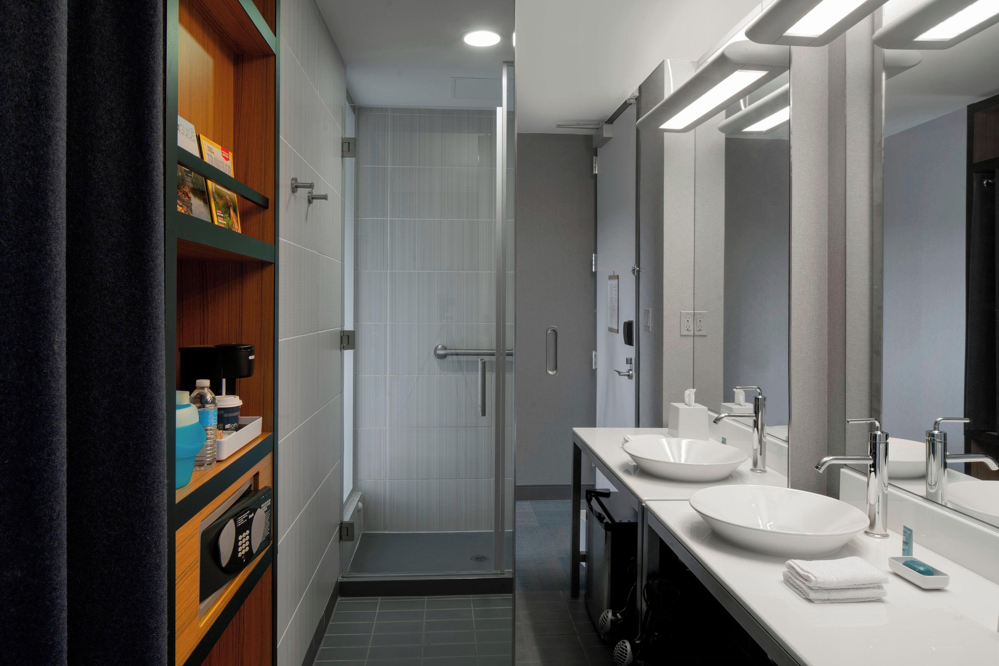 Un baño moderno con dos lavamanos, una ducha y un mueble de tocador con estantes.