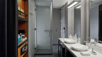 Un baño moderno con dos lavamanos, una ducha y un mueble de tocador con estantes.
