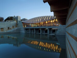 Ein modernes Gebäude mit gewölbtem Dach und Spiegelung im Wasser.