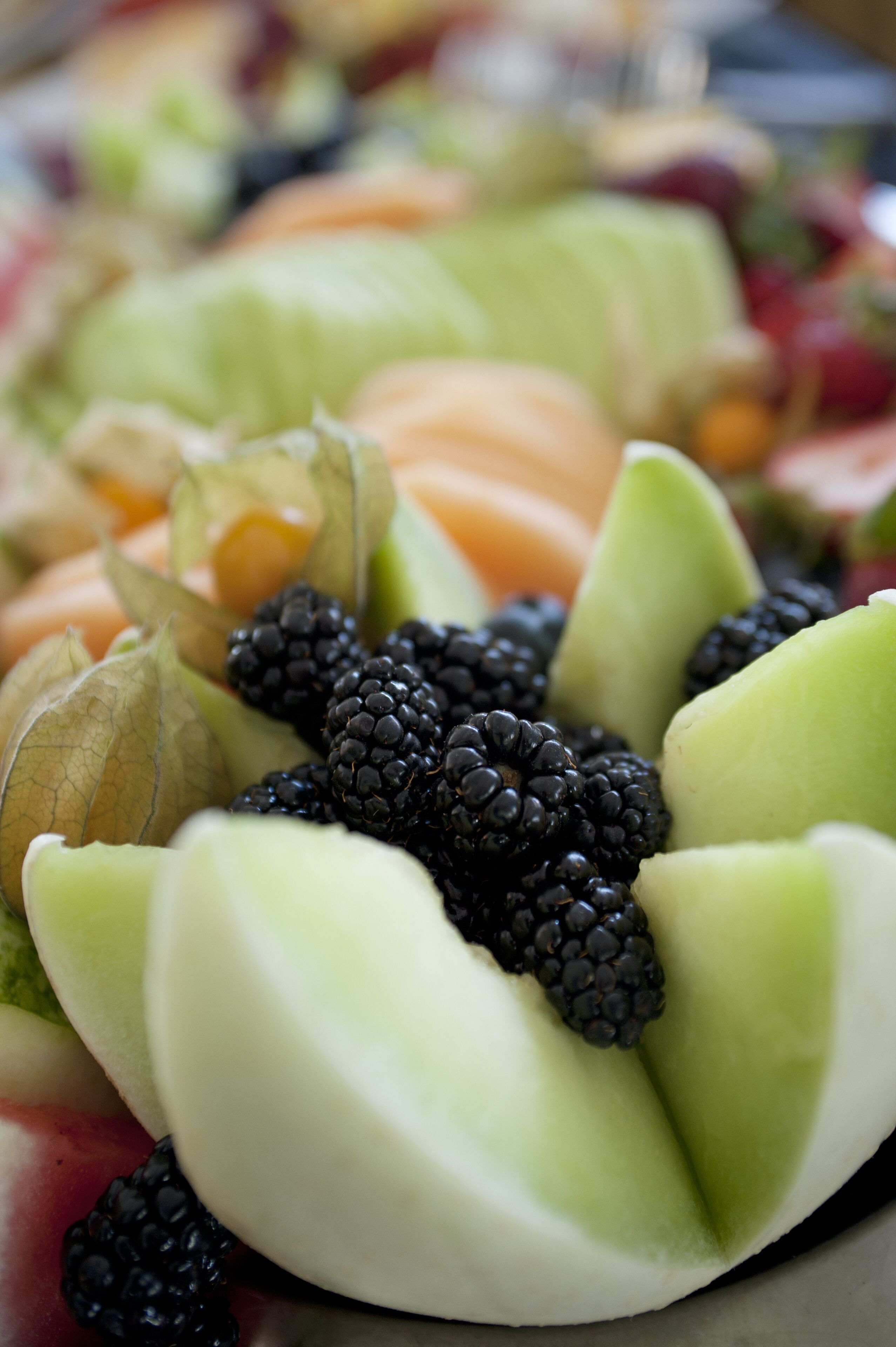A close-up of a fruit platter with sliced melon, blackberries, and other fruits.