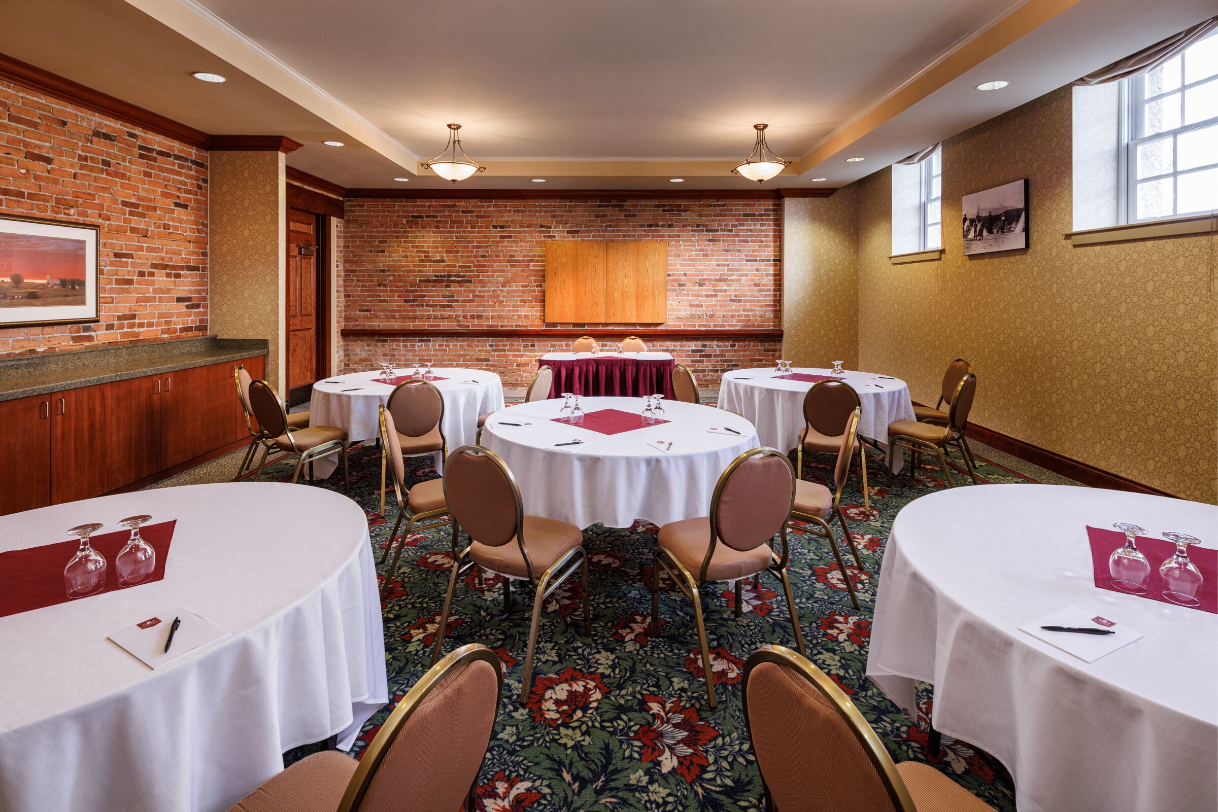 Une salle de conférence avec des tables rondes, des chaises et un mur en briques.