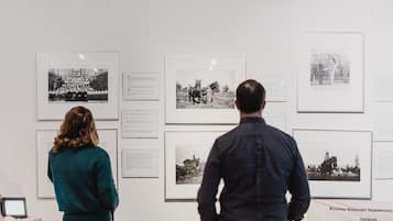 Two people viewing black and white photographs on a wall.