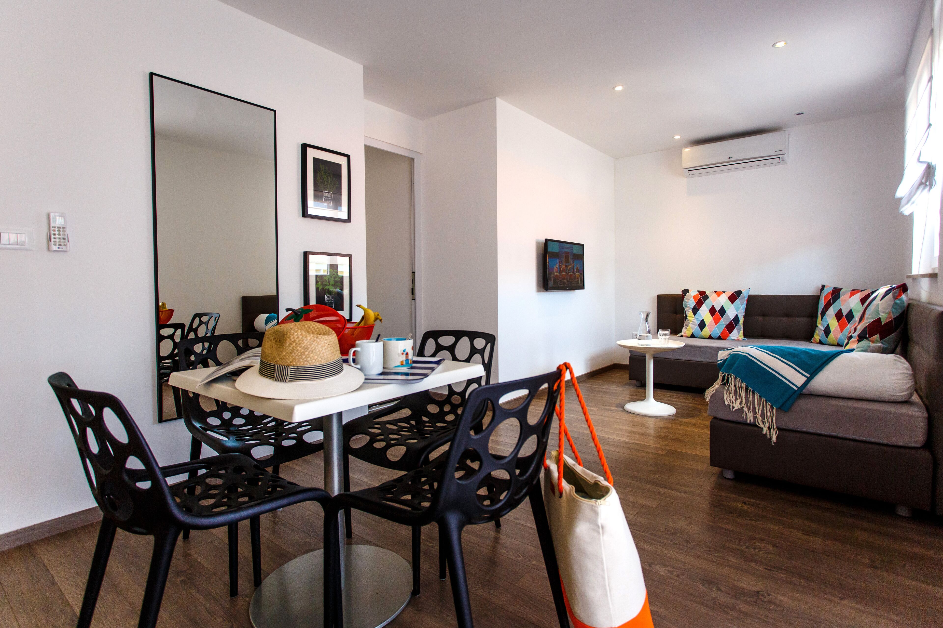 A modern living room with a dining area, featuring a sofa, chairs, a coffee table, and a large mirror.