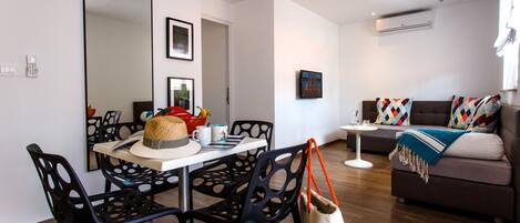 A modern living room with a dining area, featuring a sofa, chairs, a coffee table, and a large mirror.