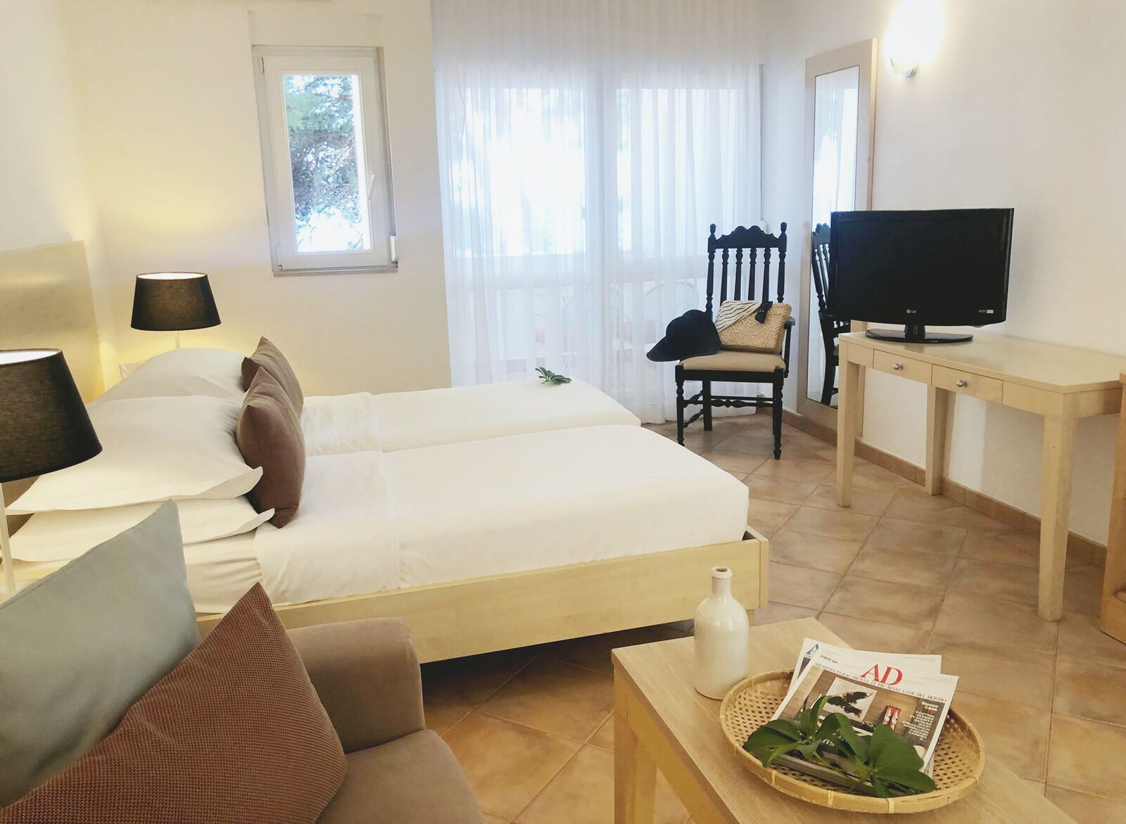 A hotel room with a bed, a desk, a television, a chair, and a window with curtains.