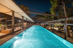 Ein Schwimmbecken mit Glasumrandung, Liegestühlen und einem überdachten Bereich mit Dach.