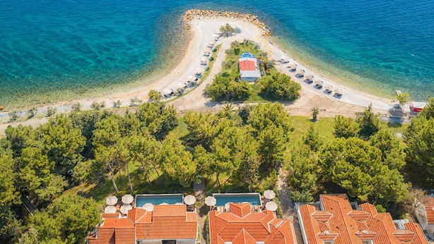 An aerial view of a coastal resort with a beach, a swimming pool, and terraced buildings. - Waterman Svpetrvs Resort (Supetar)
