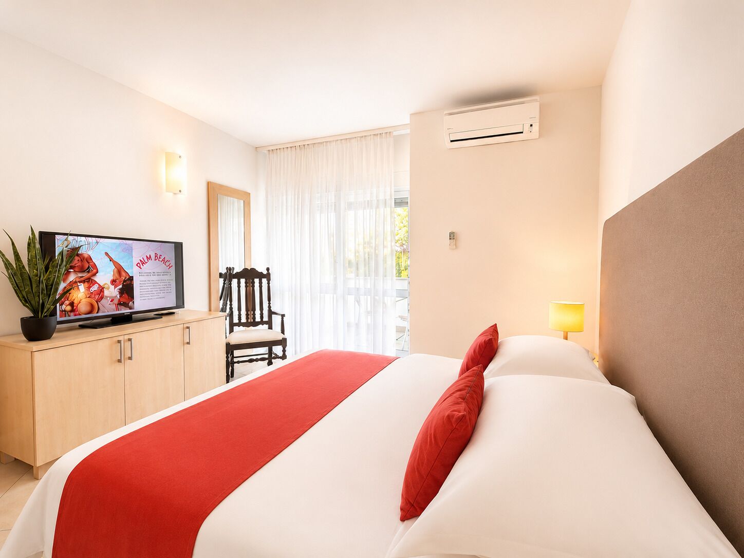 A hotel room with a bed, a television, a chair, and a window with curtains.