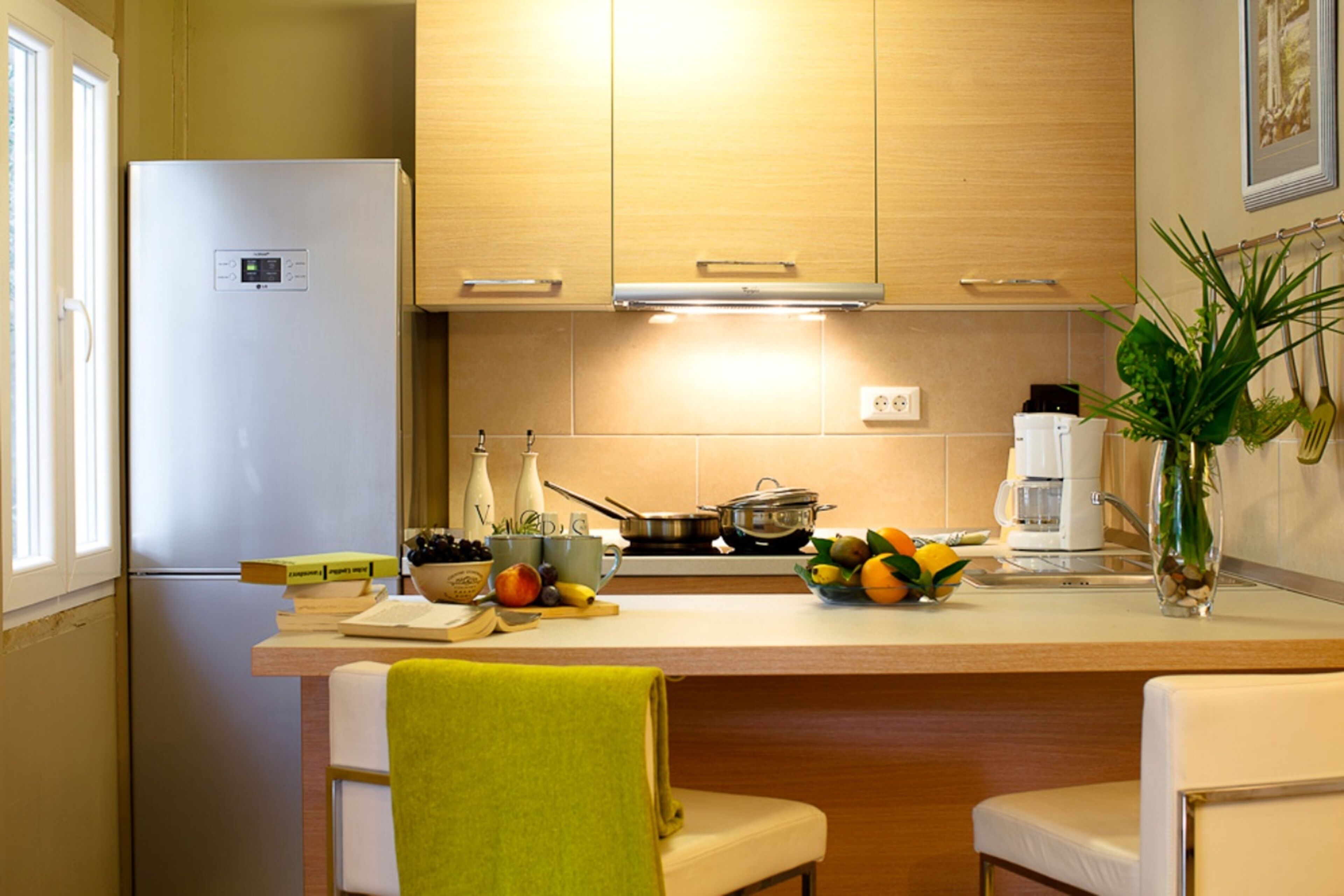 A kitchen with wooden cabinets, a white refrigerator, a countertop with a bowl of fruit, and a coffee maker.