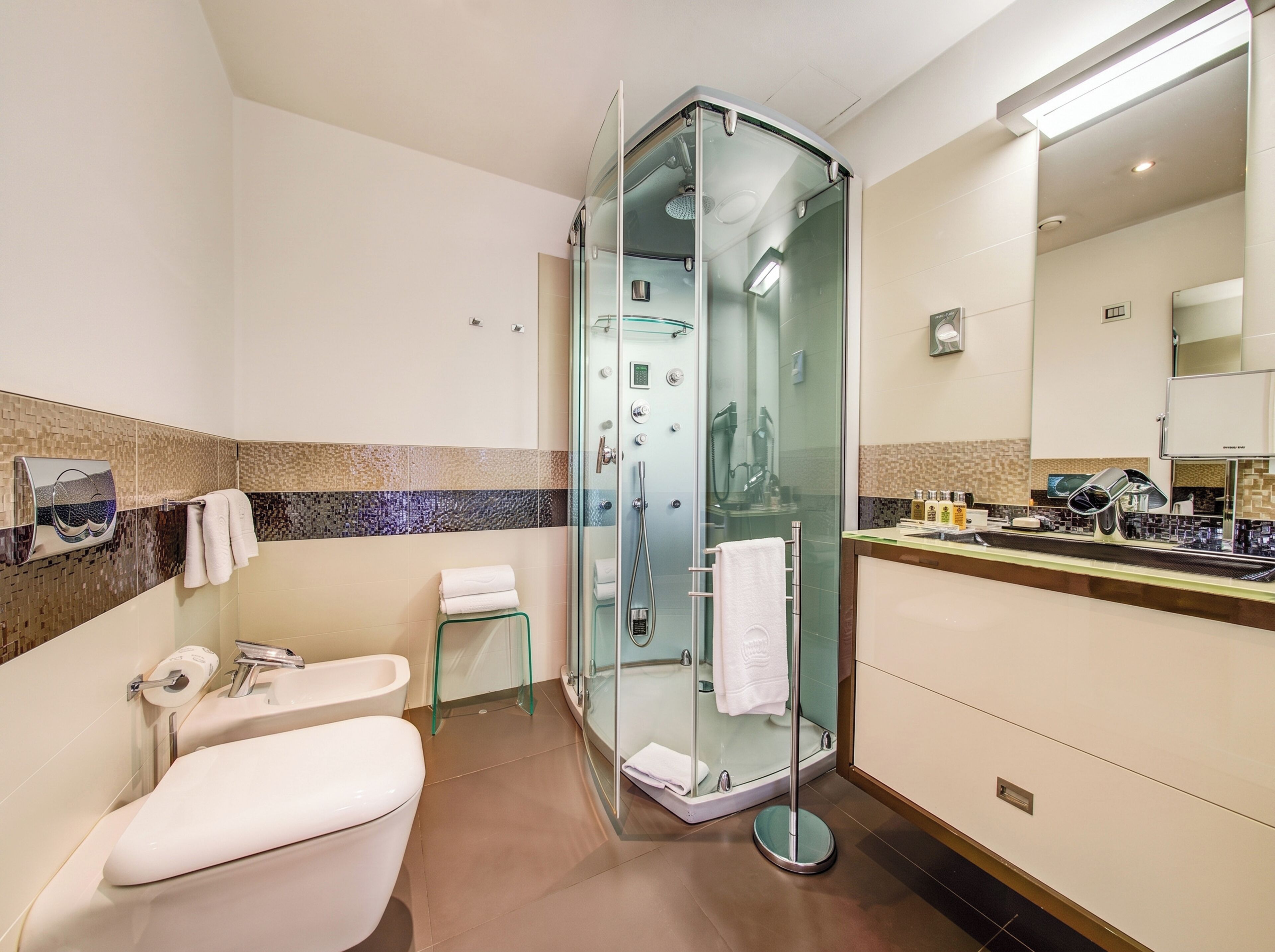 Un bagno moderno con doccia vetro, un water e un lavandino con specchio.