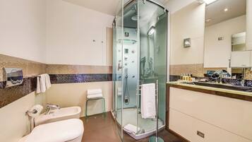 Un bagno moderno con doccia vetro, un water e un lavandino con specchio.