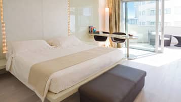 Habitación de hotel moderna con una cama grande, una mesita y un balcón con asientos.