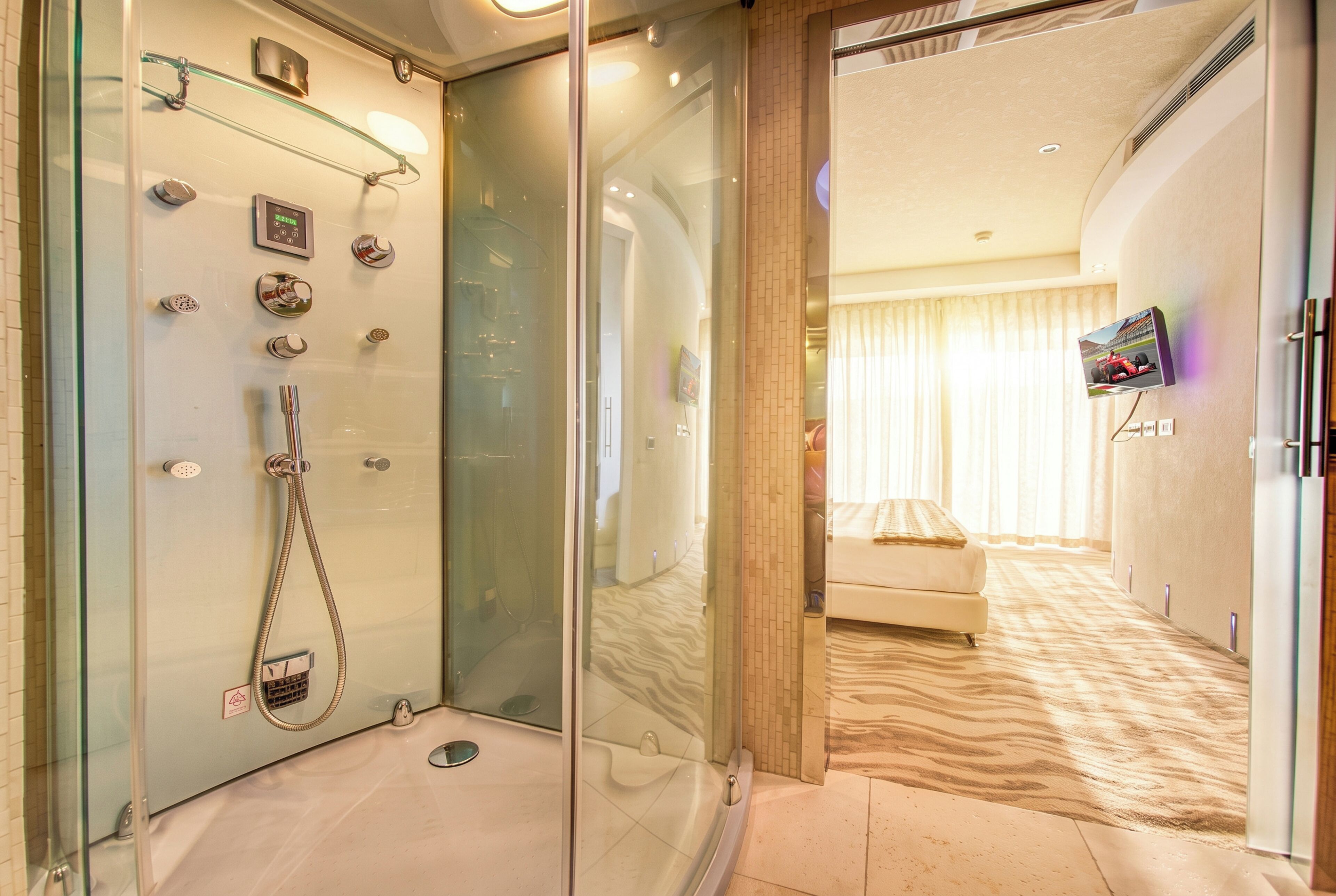 A modern bathroom with a glass-enclosed shower, a control panel, and a visible toilet.