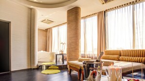 A hotel room with a large window, a bathtub, a sofa, and a breakfast tray with fruits and a bottle of champagne. - Hotel Premier & Suites (Cervia)