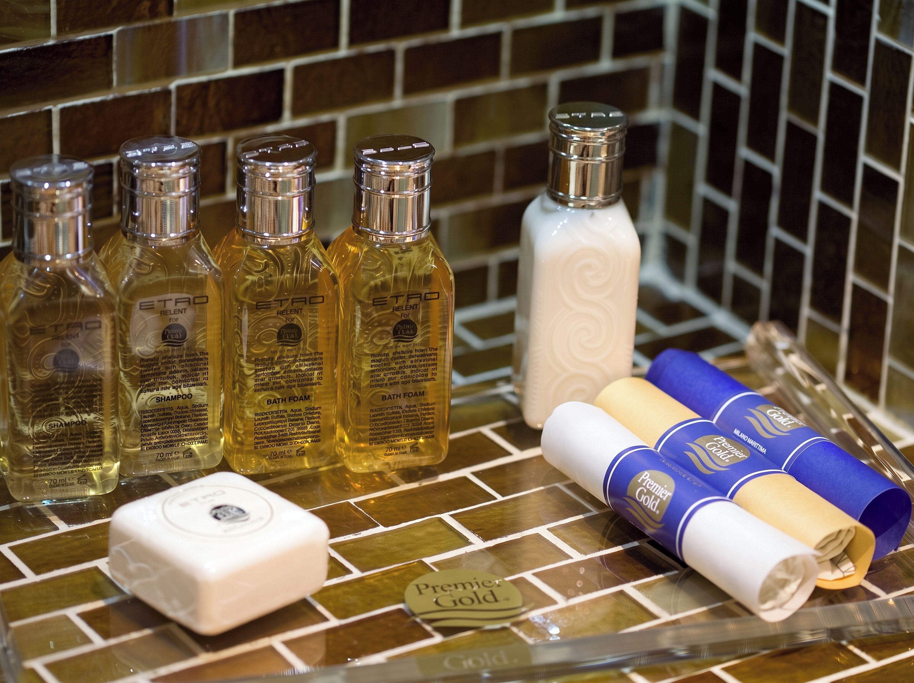 A bathroom counter with toiletries including bottles of shampoo, bath foam, and a white soap bar.