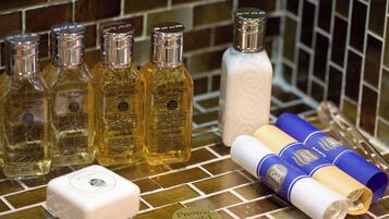 A bathroom counter with toiletries including bottles of shampoo, bath foam, and a white soap bar.