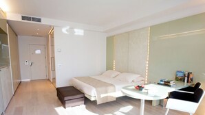 A modern hotel room with a bed, bedside table, and a small seating area. - Hotel Premier & Suites (Cervia)