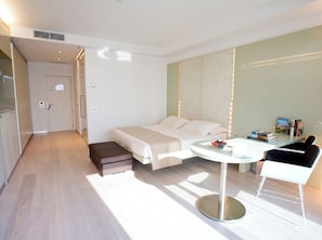A modern hotel room with a bed, bedside table, and a small seating area. - Hotel Premier & Suites (Cervia)
