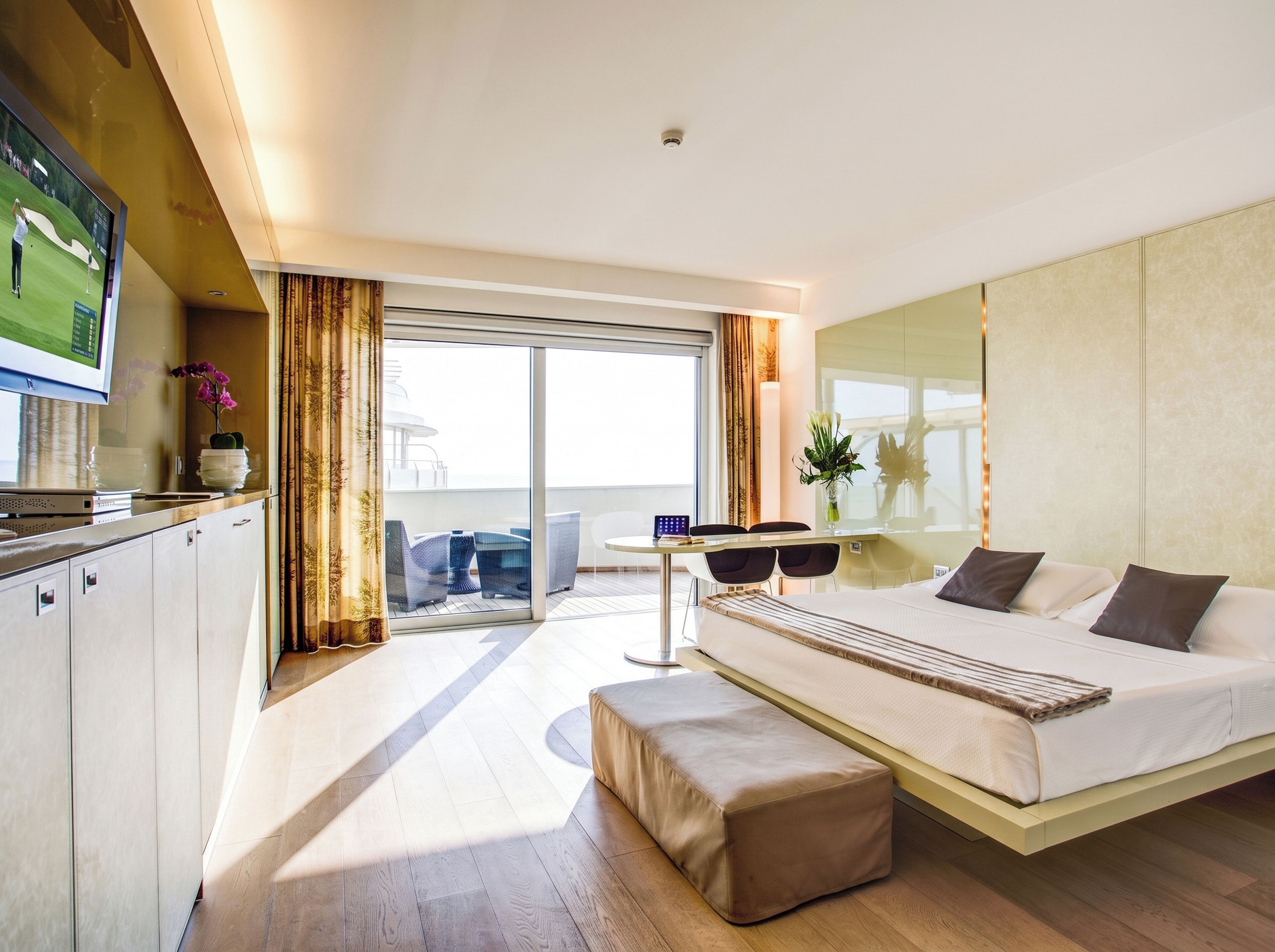 Una habitación de hotel moderna con cama, escritorio, televisión y balcón con vistas.