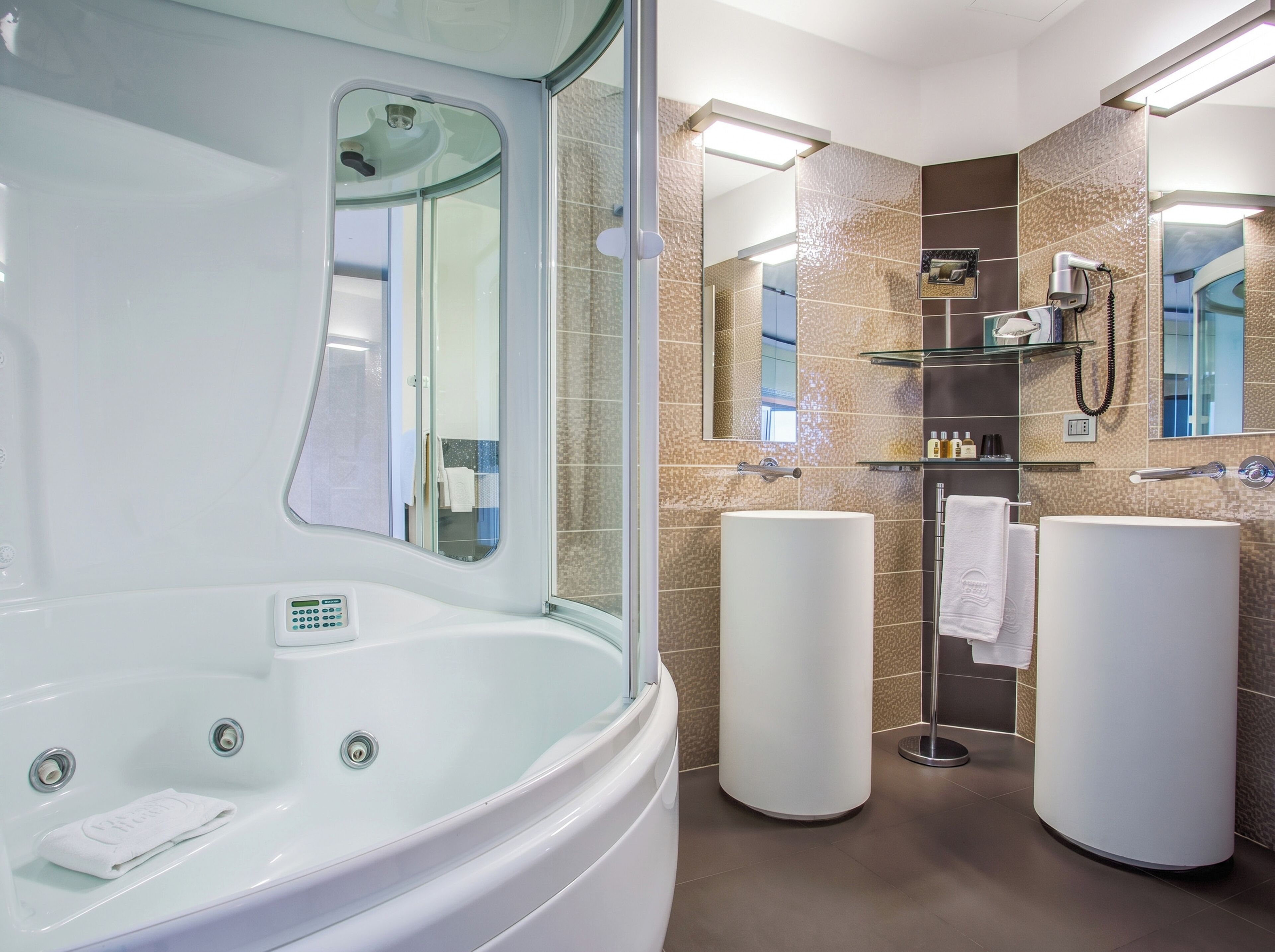 Een moderne badkamer met een groot ligbad, twee wastafels en een douchecabine van glas.