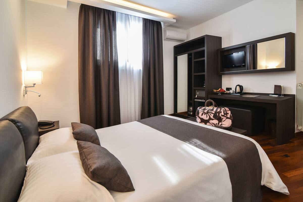 A hotel room with a bed, a desk, a television, and a wardrobe.